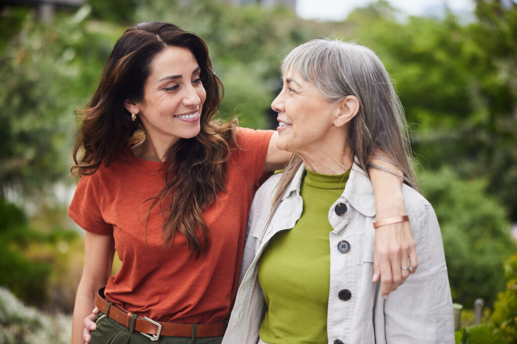 smiling woman talking with her senior mom while walking outside